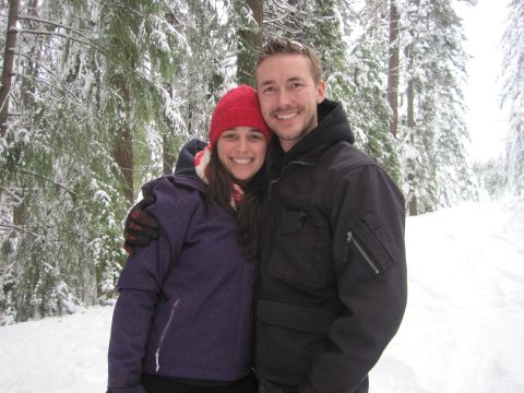1989 Ford Bronco - A couple smiles for a photo while standing in a snow-covered forest.