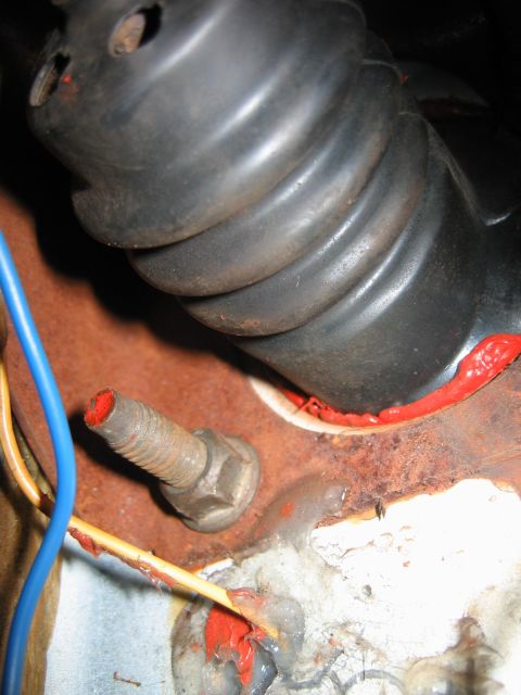 1992 Ford Bronco - Close-up of a firewall grommet sealed with red silicone, near a bolt with red paint on its tip.
