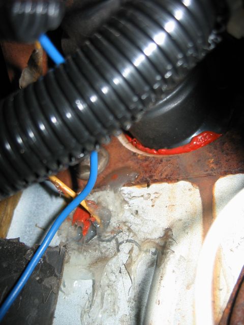 1992 Ford Bronco - Wiring harness and red sealant are visible on rusty metal in this close-up automotive shot.