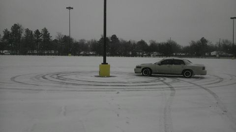 2000 Mercury Grand Marquis - A sedan drifts in circles on a snowy surface, leaving tire tracks behind.