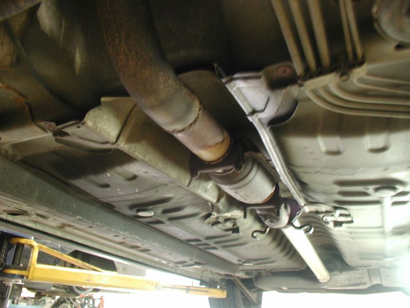 Underside view of a car's exhaust system, showing the catalytic converter and pipes