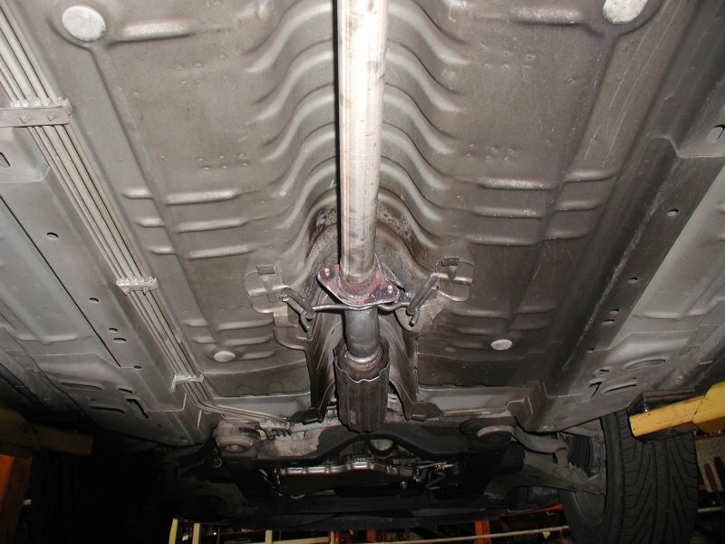 Underside of a vehicle showing the exhaust system and catalytic converter. The vehicle is viewed from below, angled slightly towards the front