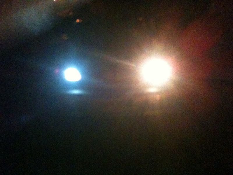 Two bright lights illuminated at night, one blue-white, one yellow-white