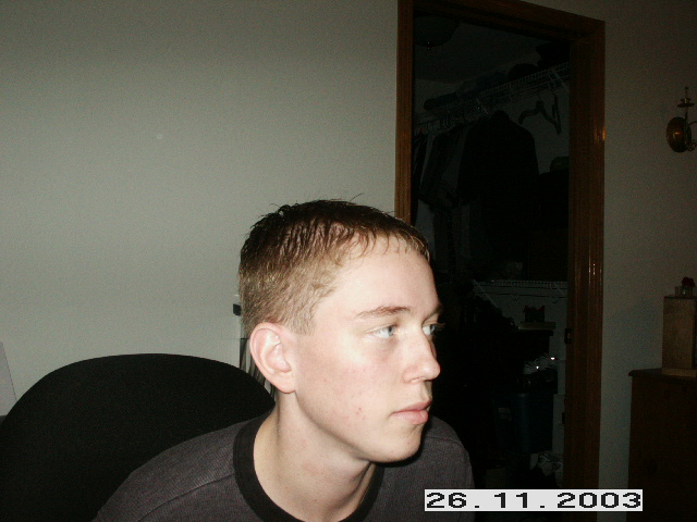 Young man in profile, looking to the right. A closet is visible behind him