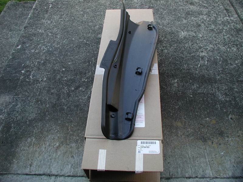Black plastic car part with clips, sitting on cardboard boxes. Part number 15784785 visible