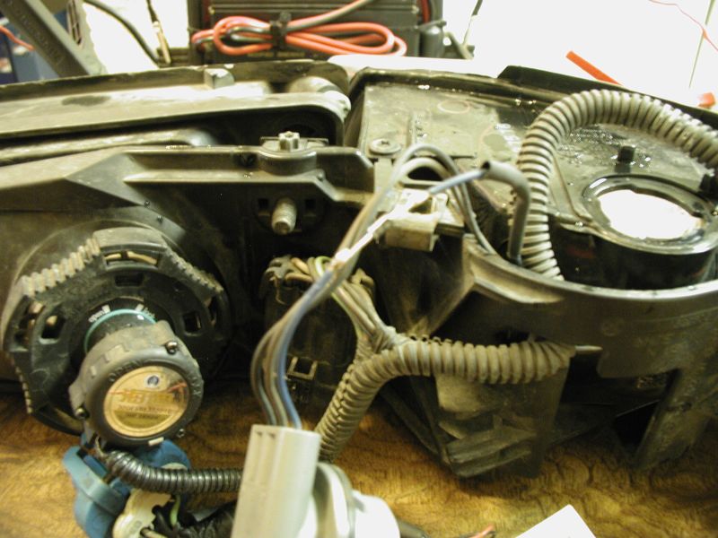 Close-up of a car headlight assembly with wiring and a circular component with text