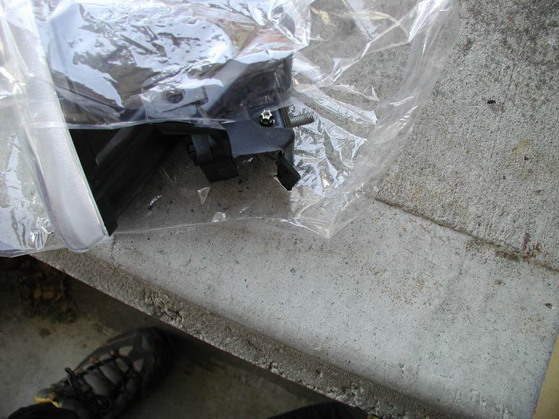 Headlight housing part in plastic packaging, resting on concrete
