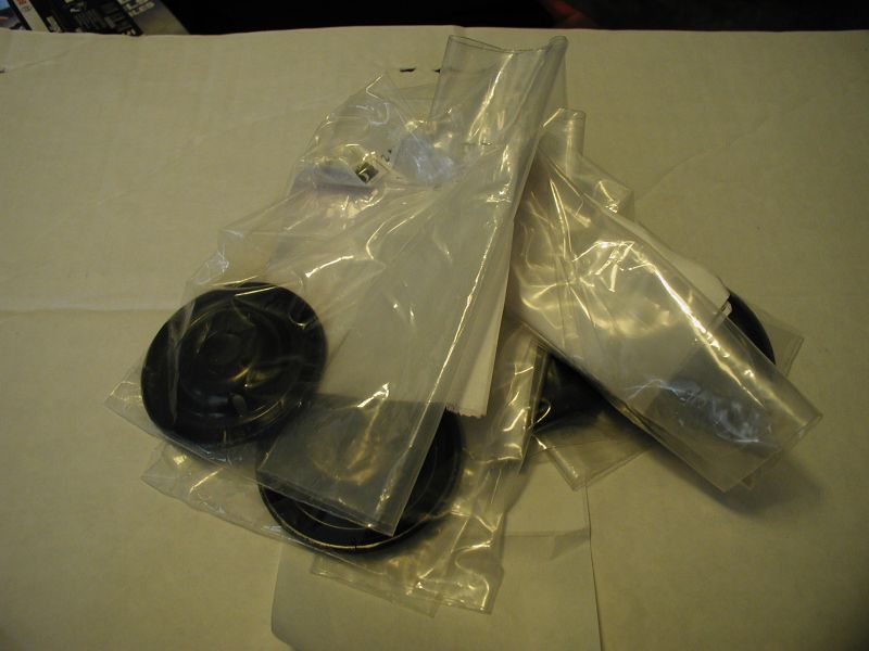 Several black automotive parts, possibly seals or caps, in clear plastic packaging