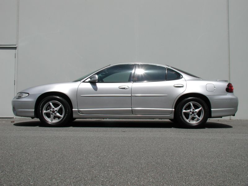 Side view of a silver 2002 Pontiac Grand Prix parked against a wall