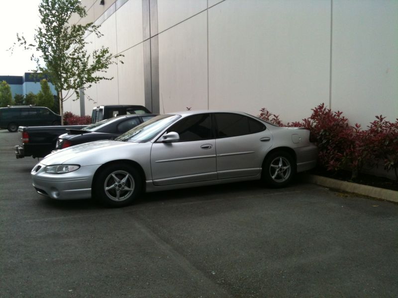 Silver 2002 Pontiac Grand Prix sedan parked next to a building