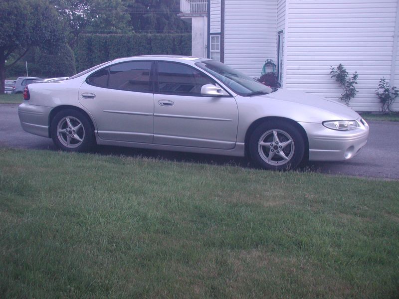 Silver 2002 Pontiac Grand Prix parked on grass next to a house
