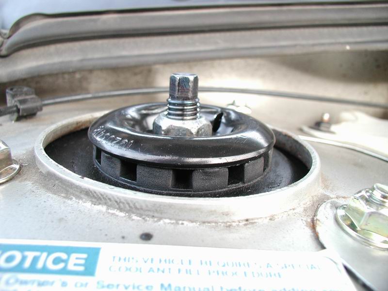 Close-up of a car's strut mount with a bolt and nut
