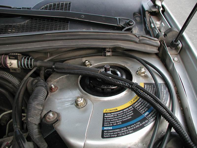 Engine bay with a sticker indicating R-134a refrigerant and General Motors Corporation