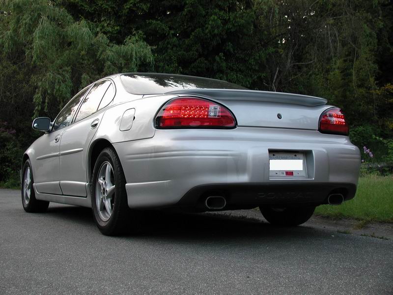 Rear view of a silver 2002 Pontiac Grand Prix with a spoiler and dual exhaust pipes