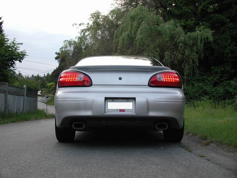 Silver sedan rear view, showing taillights, dual exhaust, and a license plate
