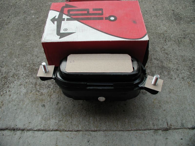 Black car part with bolts and a red box with logo