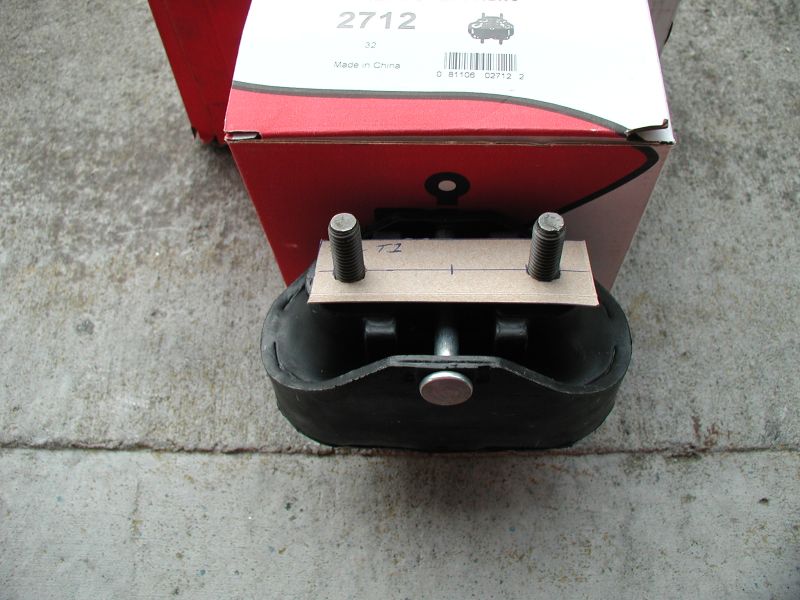 Engine mount part with two bolts and a piece of cardboard marked 'TZ'. Box in background has part number 2712