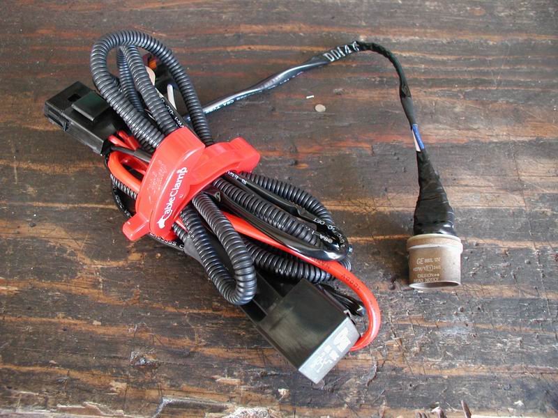 Wiring harness with red cable clamp and GE bulb socket on a wooden surface.