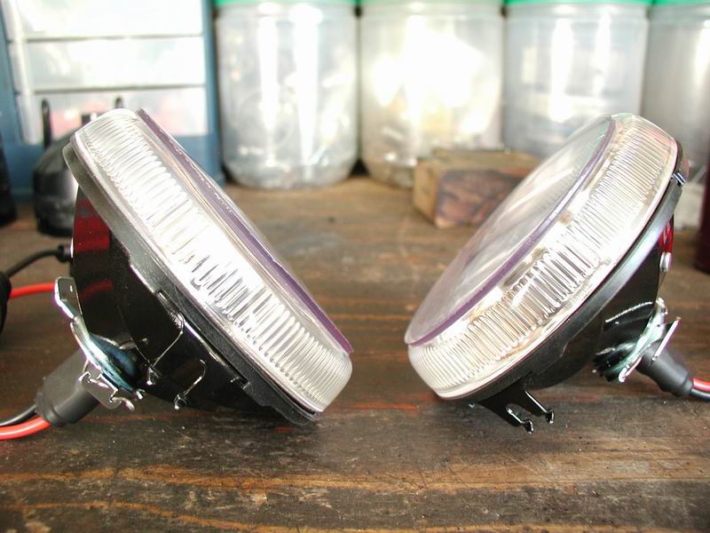 Two car headlights, possibly for a 2002 Pontiac Grand Prix, resting on a wooden surface