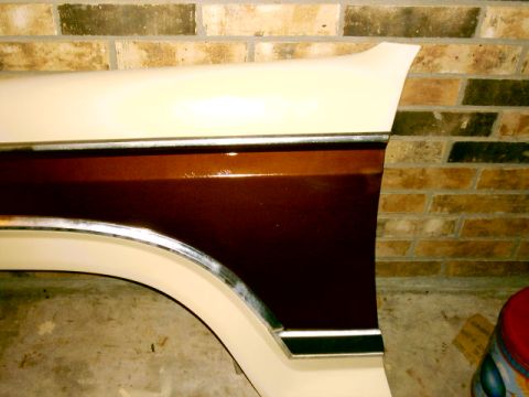 1980 Ford Bronco - Freshly painted truck front fender leaning against a brick wall, sprayed cream white with a glossy metallic dark brown two-tone side panel…