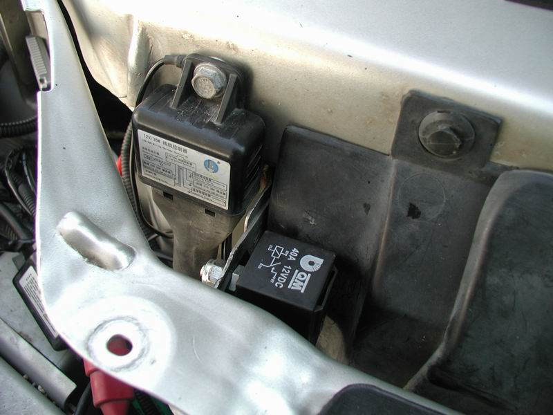 Close-up of a QM 40A 12VDC relay and a black control module with Chinese text, mounted in an engine bay