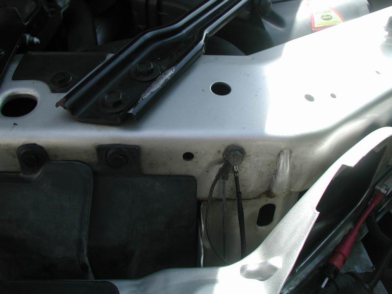 Close-up of car's engine bay showing metal brackets and wiring
