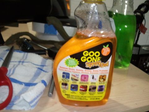 1994 Ford Bronco - A bottle of Goo Gone spray gel sits on a table with cleaning supplies and other bottles in the background.