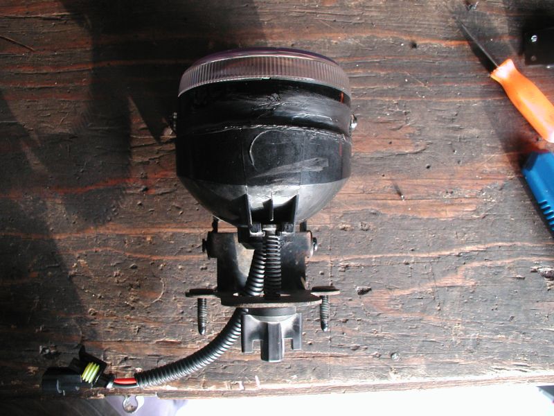aftermarket fog light assembly with wiring harness on wooden surface