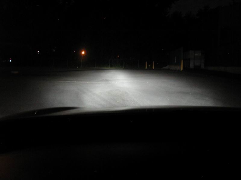 Headlights illuminate a dark road at night. Supermotors.net logo visible