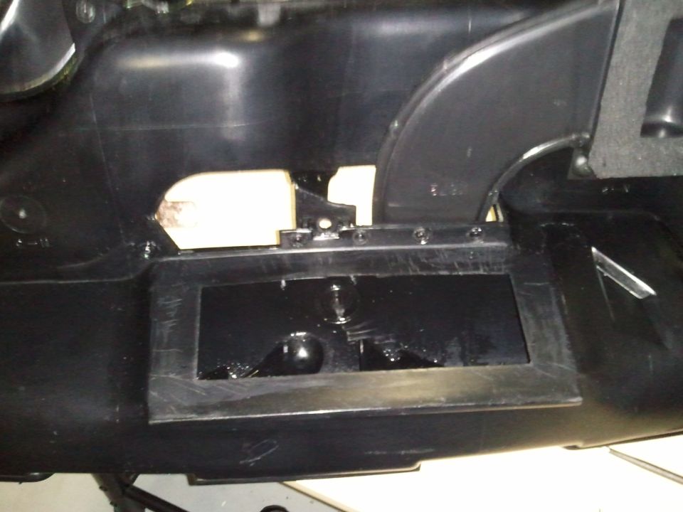 Close-up of a black plastic dashboard section with an open rectangular cutout and some metal brackets