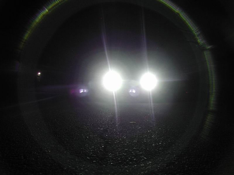 Two cars with bright headlights on a dark road