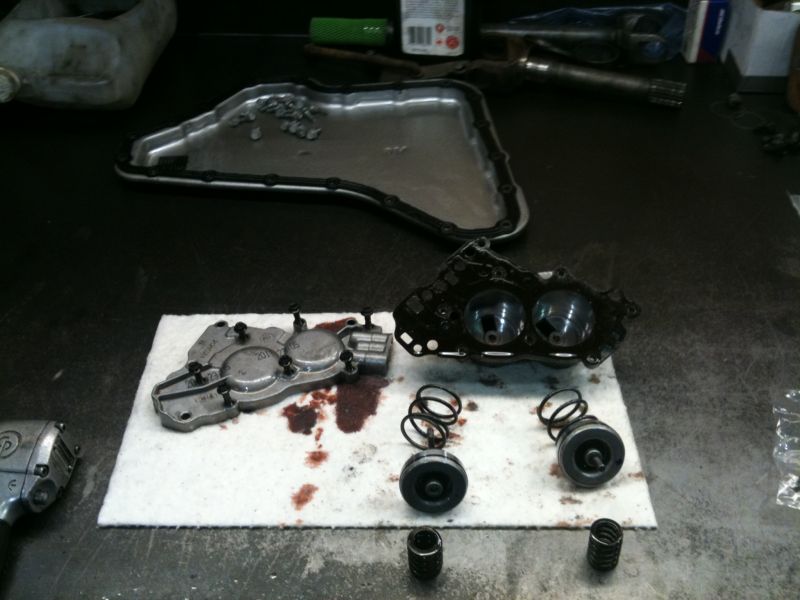 Disassembled transmission valve body and pan with springs and plungers on a workbench