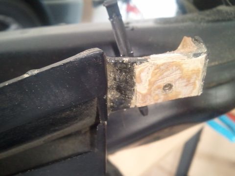 1994 Ford Bronco - Repair made to a car interior trim piece using a wooden block and screw.