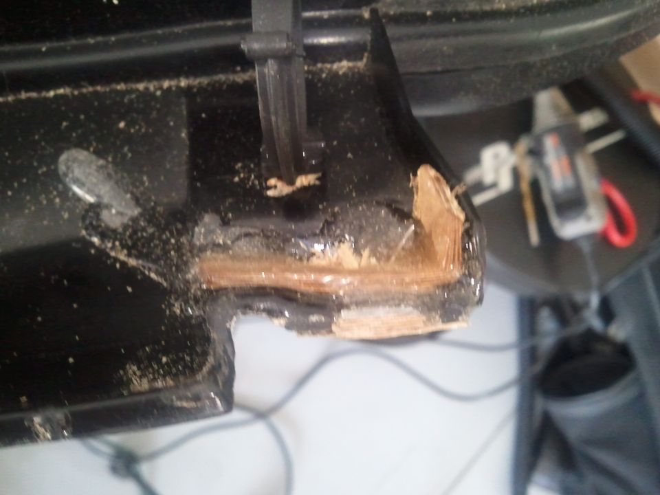 close-up of broken black plastic trim with wood exposed