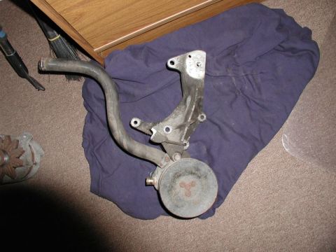 1990 Ford F-250 - This is an alternator bracket with a hose attached, likely a replacement part for a vehicle.