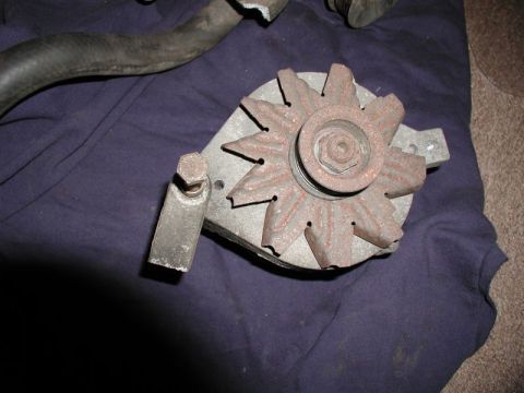 1990 Ford F-250 - Close-up of a rusty alternator part, likely removed from a vehicle.