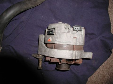 1990 Ford F-250 - A used automotive alternator is shown resting on a purple cloth, with a black hose nearby.
