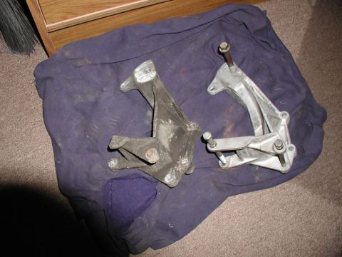 1990 Ford F-250 - Two metal alternator mounting brackets are shown on a purple cloth.