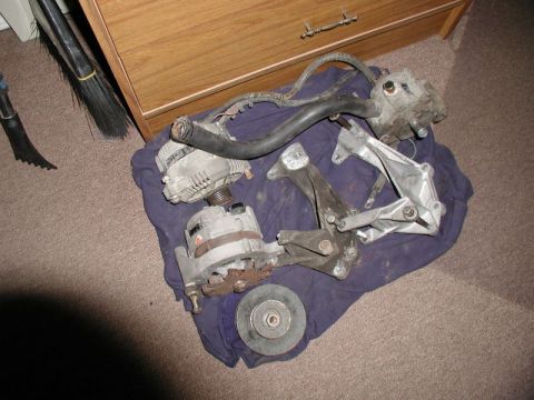 1990 Ford F-250 - Several automotive parts, including two alternators and mounting brackets, are displayed on a cloth.