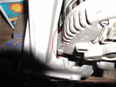 1990 Ford F-250 - Close-up of an alternator part, with a red circle highlighting a bolt and a Shell oil bottle visible.
