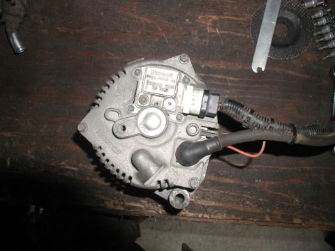 1990 Ford F-250 - Motorcraft alternator, part number F5TF-10300-AA, shown on a workbench with tools.