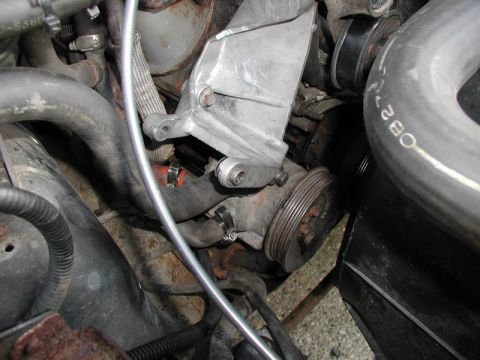 1990 Ford F-250 - Engine bay detail showing an alternator bracket and pulley assembly with surrounding hoses and wiring.