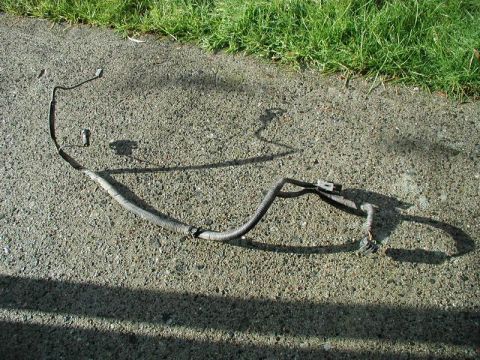1990 Ford F-250 - A detached automotive wiring harness lies on a paved surface, with grass visible in the upper portion of the image.