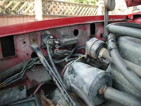 1990 Ford F-250 - Close-up view of engine bay components in a red vehicle, including a fuse box and hoses.