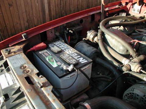 1990 Ford F-250 - Close-up of an engine bay an Interstate battery and various hoses and components.