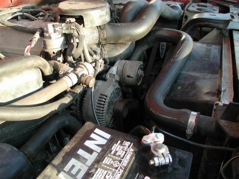 1990 Ford F-250 - Close-up view of an engine bay, focusing on the alternator and battery components.