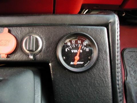 1990 Ford F-250 - A close-up view of a vehicle's dashboard, a voltage meter and power outlets.