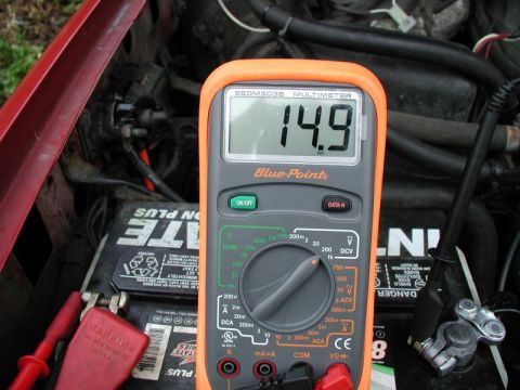 1990 Ford F-250 - A multimeter reads 14.9 volts while connected to a car battery, indicating charging system status.