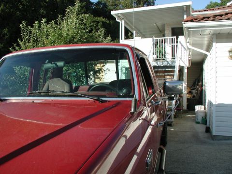 1990 Ford F-250 - A red pickup truck is parked in a driveway next to a house with an outdoor staircase.