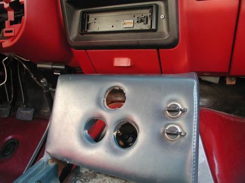 1990 Ford F-250 - Interior view of a vehicle's center console, showing an aftermarket radio and cutouts for cup holders.